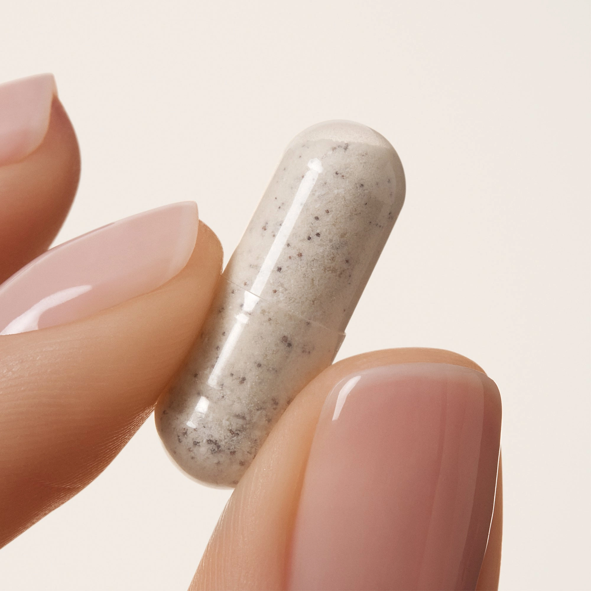 Fingers holding a speckled capsule