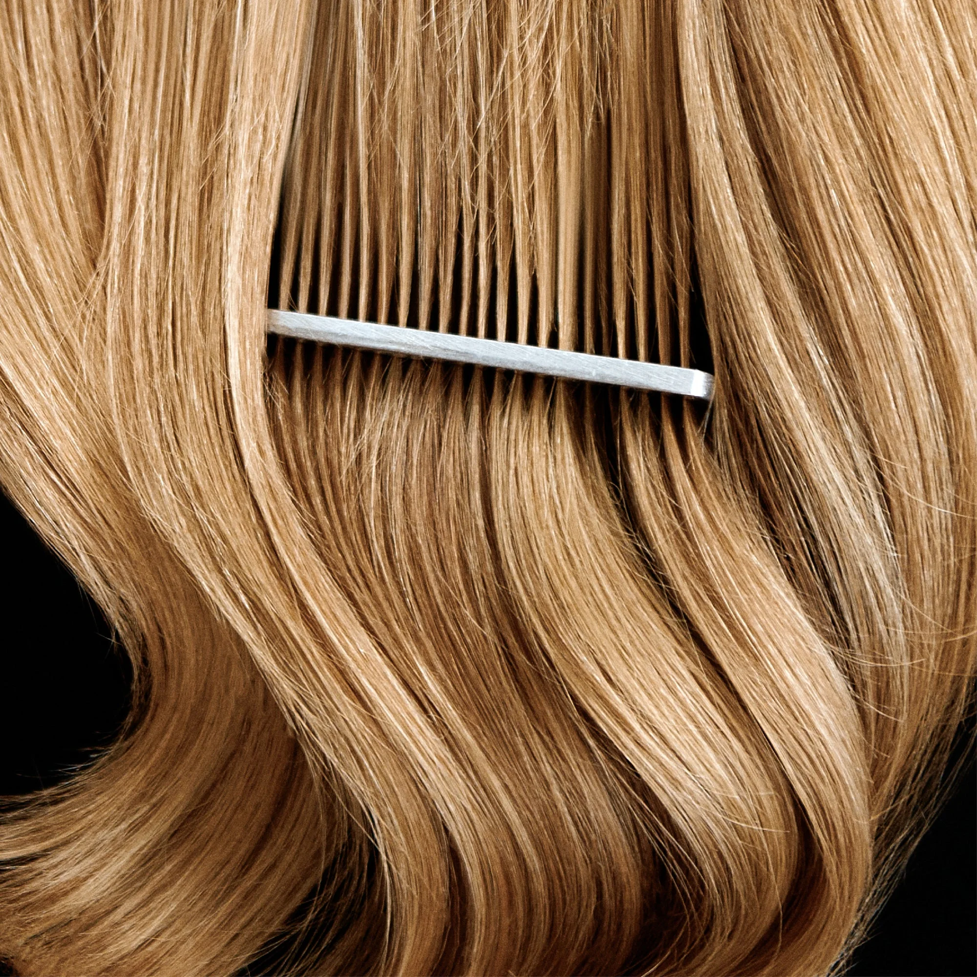 Blonde hair with a comb running through it, on black